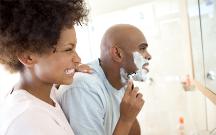 picture of couple looking in the mirror, man is shaving, using shaving foam